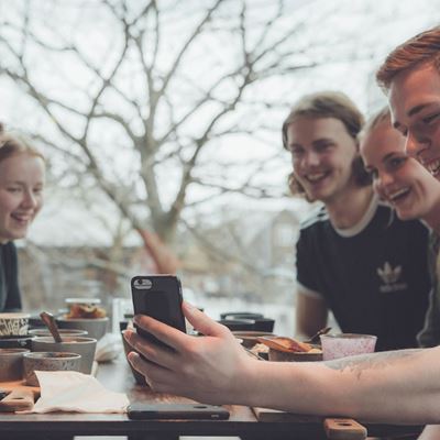 Unge mennesker og en mobil på en café