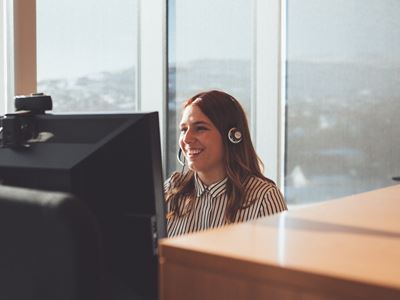 Kvinde foran computer på kontor med headset
