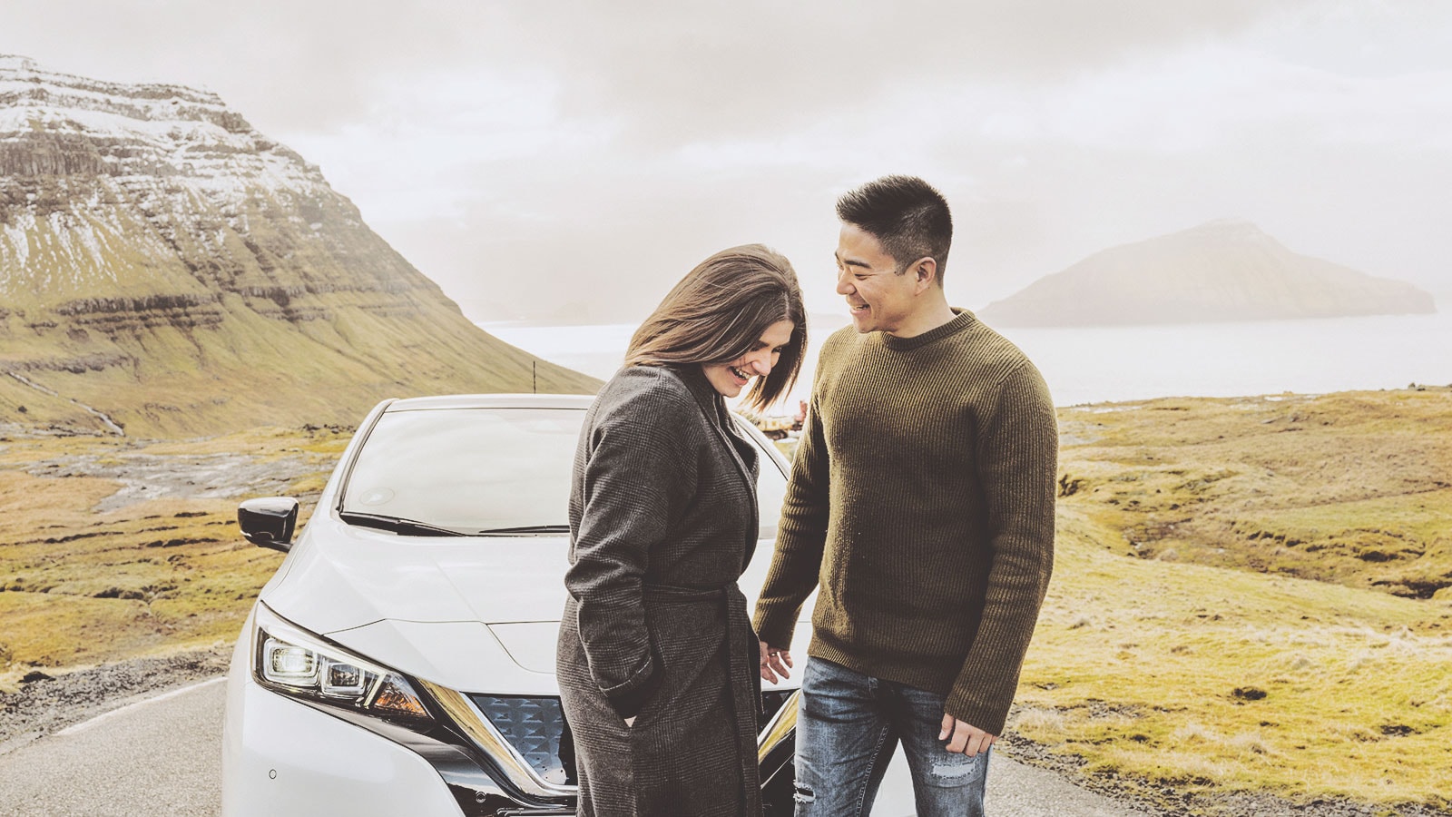 Et par står foran en ny elbil ude i den færøske natur.
